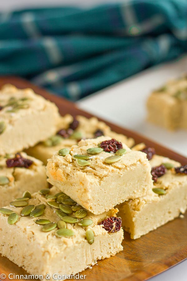 side view of stacked vegan chickpea blondies topped with cranberries and toasted pepitas