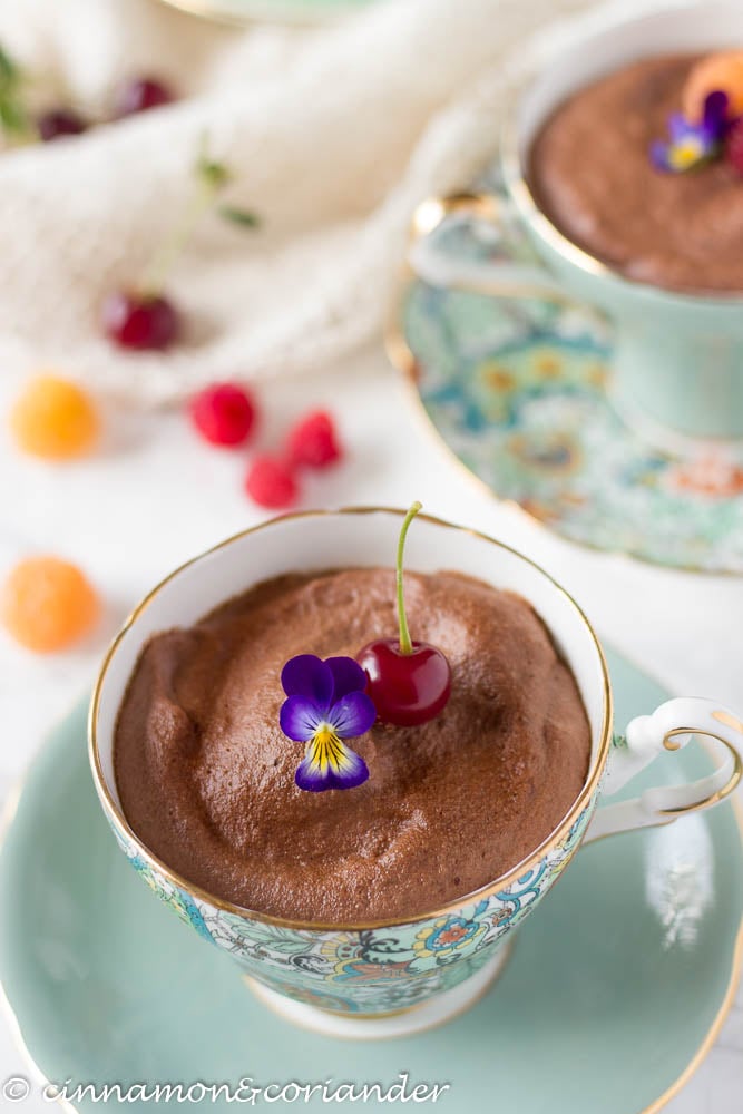 Best Vegan Aquafaba Chocolate Mousse served in a china tea cup with a fresh cherry and and edible flower on top