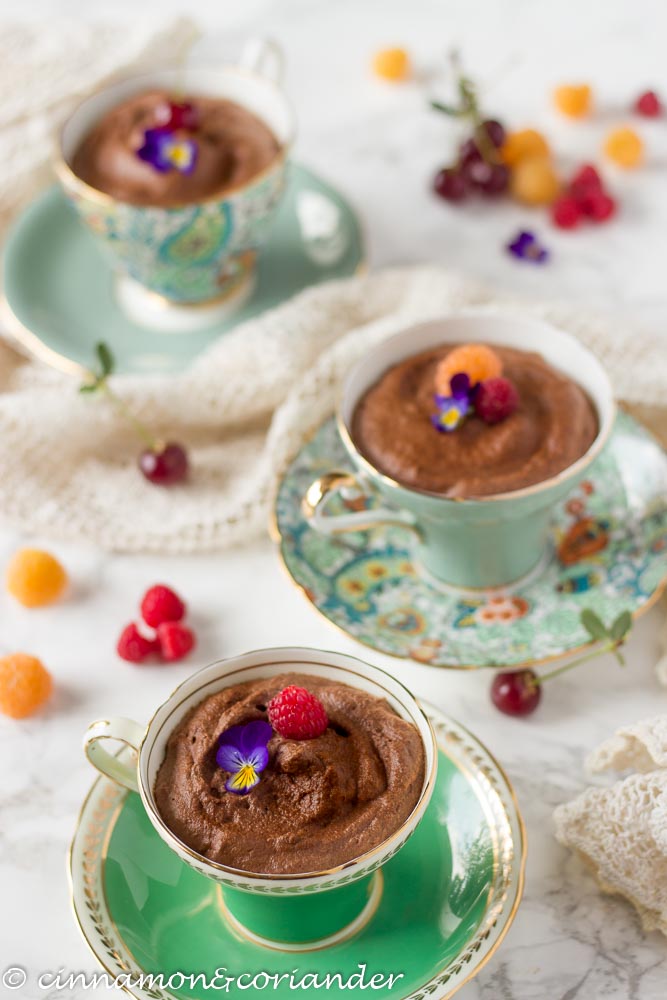 Vegan Aquafaba Chocolate Mousse decorated with edible flowers and raspberries and served in colourful tea cups