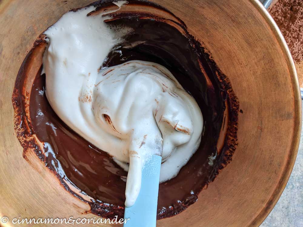 whipped vegan egg whites being folded into dark chocolate ganache for making mousse