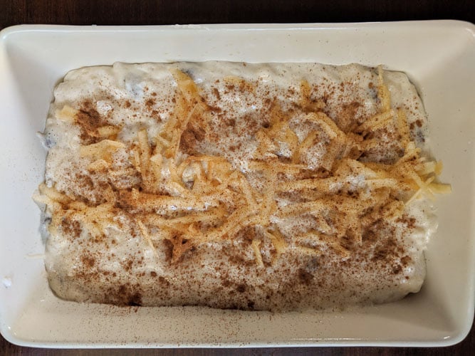 rice pudding in a casserole topped with grated apple and cinnamon