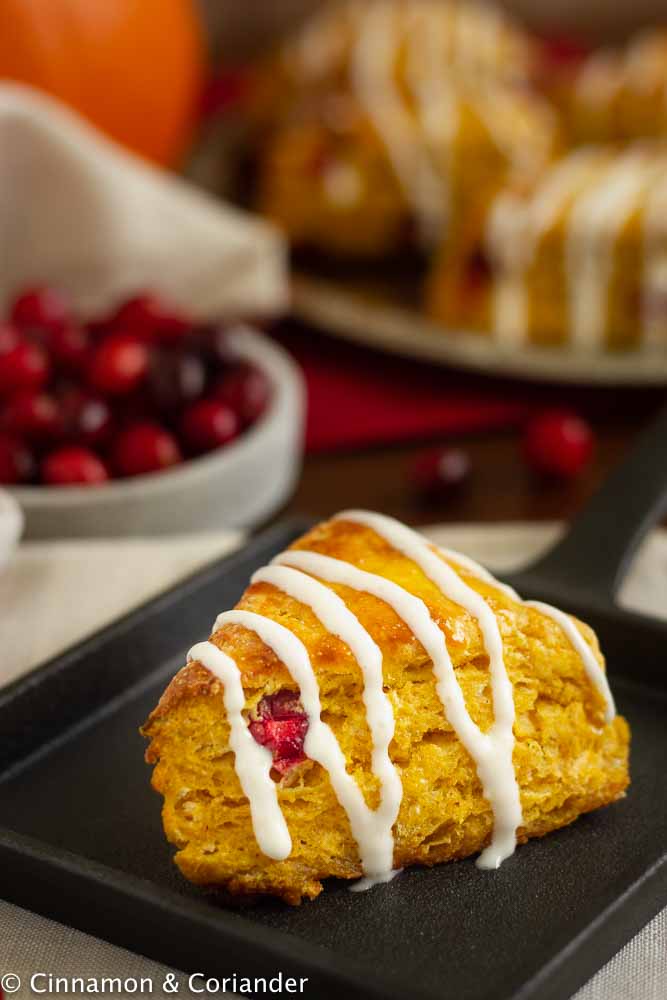 Close up of Cranberry Pumpkin Scone drizzled with cream cheese icing on a black plate
