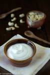 easy vegan sour cream in a little dish with a wooden spoon and cashew nuts on the side