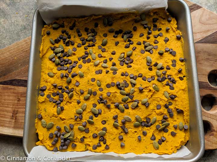 vegan healthy pumpkin bars being topped with chocolate chips and pepitas