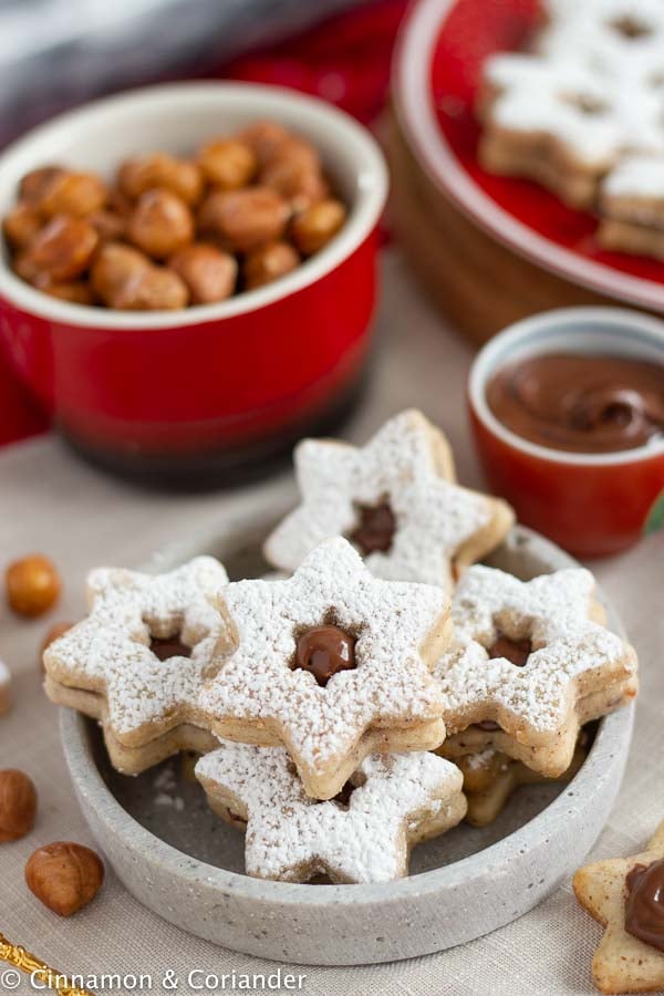 Star-shaped Hazelnut Sandwich Cookies with Nutella Filling in a white bowl