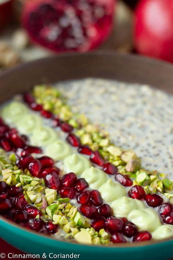vegan overnight oats topped with pistachios, pistachio creme and pomegranate arils - close-up