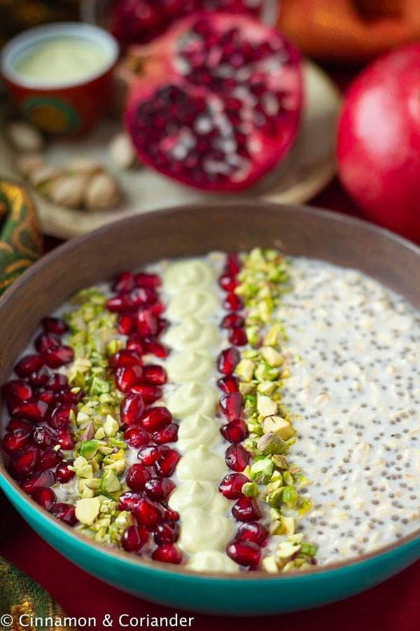 close-up of a bowl of healthy vegan overnight oats with pistachio creme and pomegranate arils