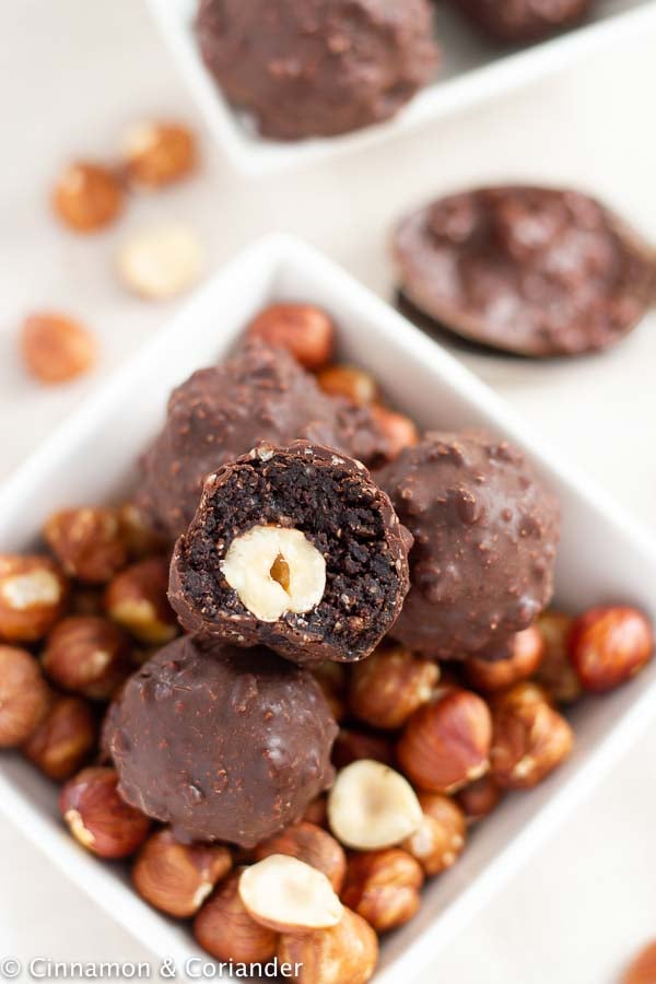 Healthy Homemade Ferrero Rocher Hazelnut Truffles in a small dish with toasted hazelnuts
