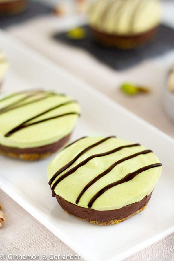 Nutella Pistachio Vegan Raw Mini Cheesecakes with chocolate topping on a white plate 