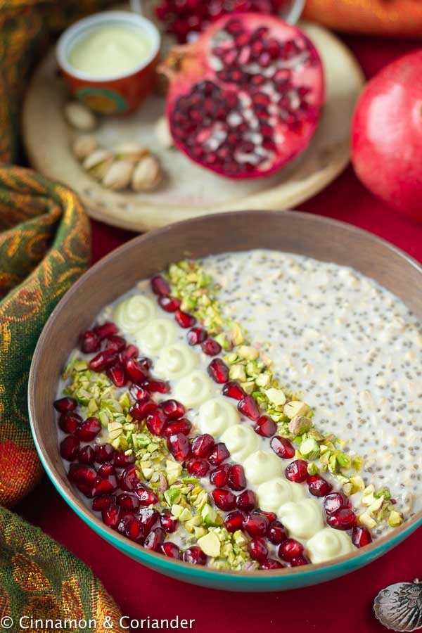 healthy vegan overnight oats with pistachios and pomegranate arils in a wooden bowl 