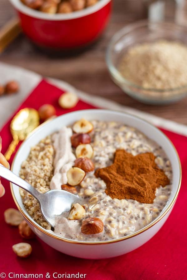 a spoon being dipped into a bowl of vegan hazelnut cinnamon overnight oats