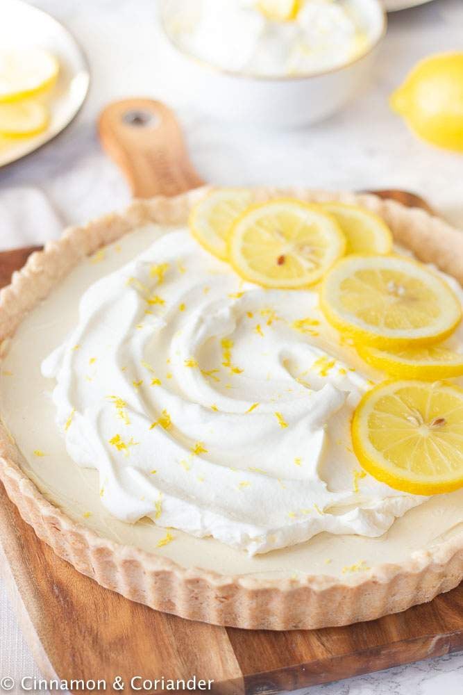 Vegan Lemon Tart with Coconut Whipped cream on a wooden chopping board
