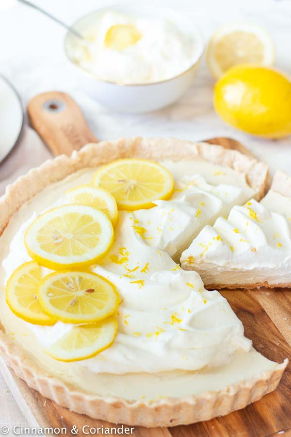 vegan lemon tart with coconut whipped cream being cut into slices