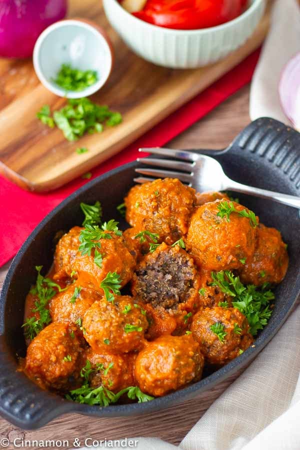 Healthy Vegan Meatballs with Black Beans tossed with roasted bell pepper sauce in a black dish 
