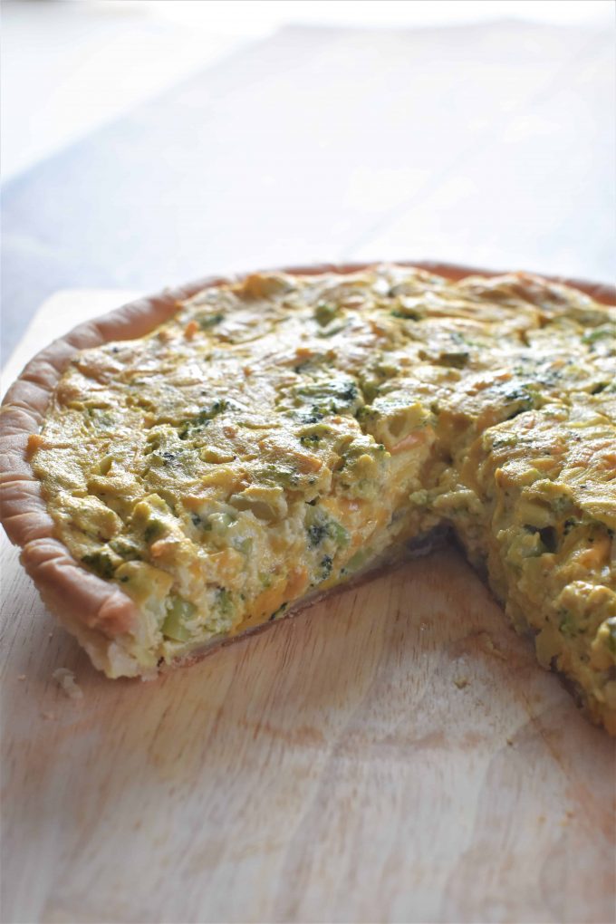 side view of cheesy vegan broccoli quiche with one piece missing 