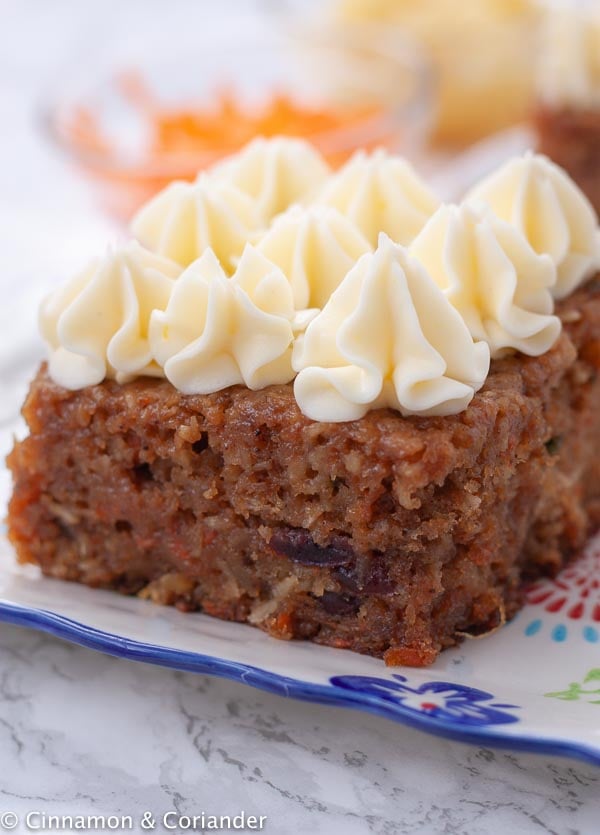 close-up of a slice of moist carrot cake with piped cream cheese frosting