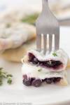 Close-up of two traditional Polish blueberry pierogi topped with sour cream
