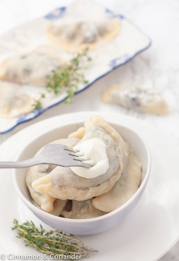 homemade Polish Blueberry Pierogi in a small bowl topped with sour cream