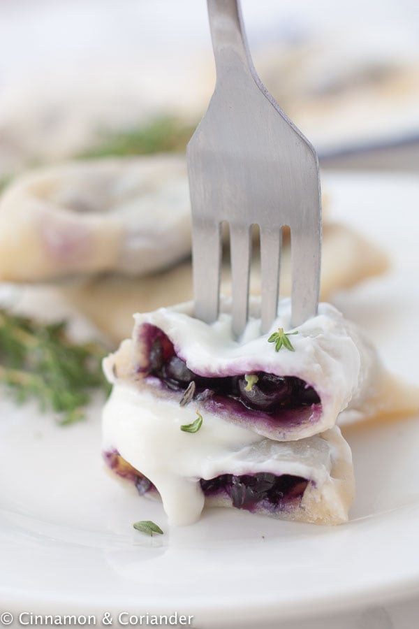 a blueberry pierogi on a white plate with blueberry filling oozing out