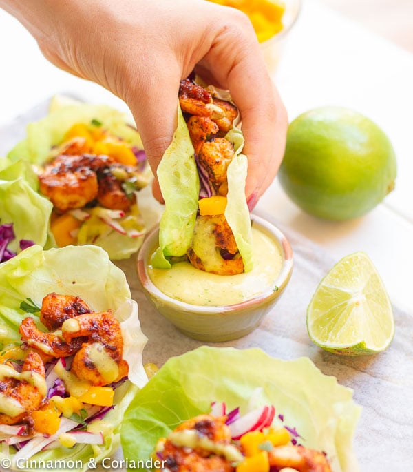 Healthy Grilled Chipotle Shrimp Lettuce Wraps being dipped into mango cilantro sauce