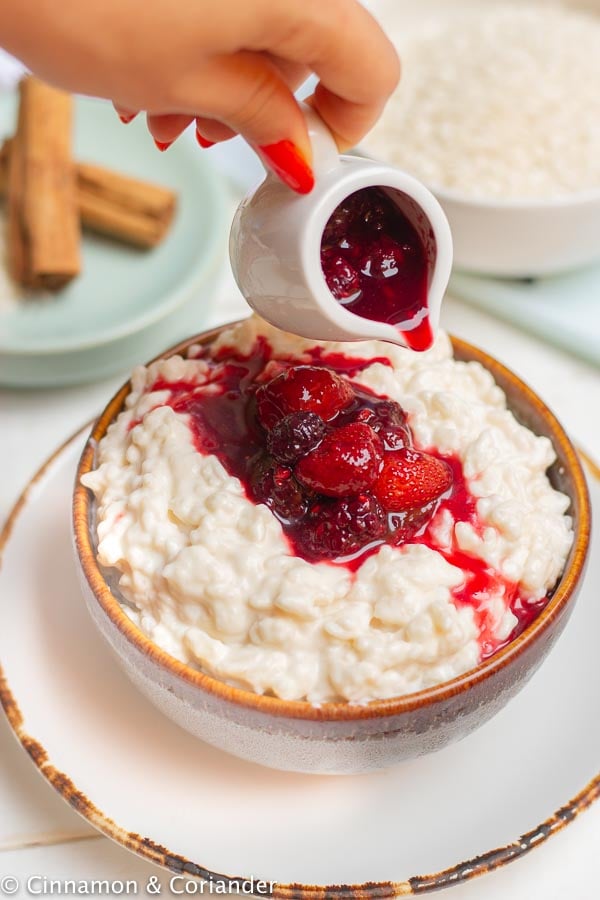 Berry Sauce being poured on top of a bowl with healthy sugar-free Instant Pot Rice Pudding