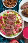 overhead shot of healthy autumn steak salad drizzled with maple raspberry vinaigrette