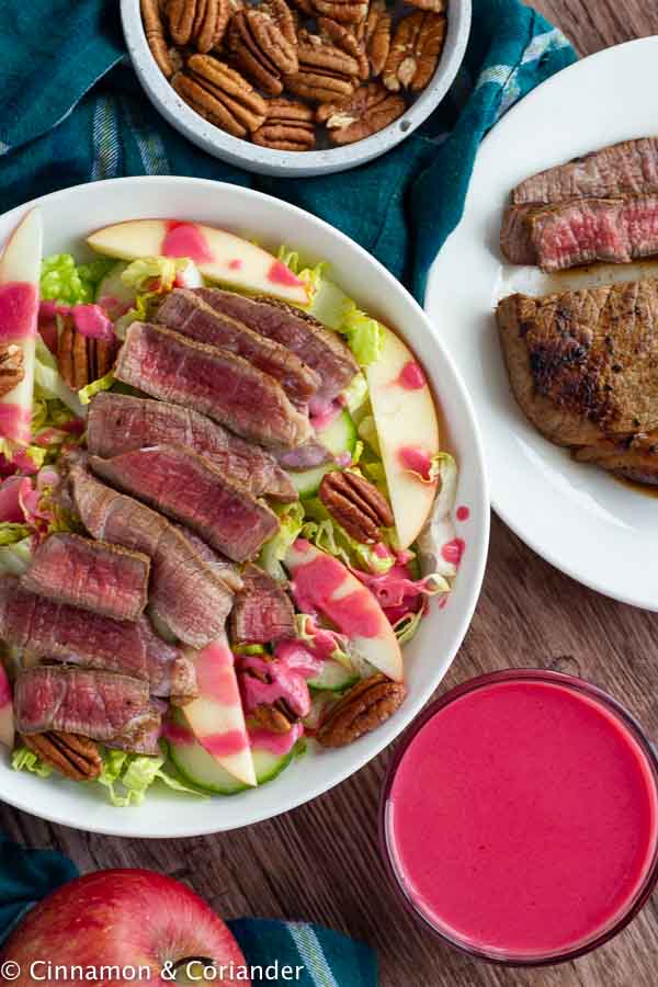 overhead shot of a healthy steak salad with perfect pan-seared steak strips, apples, pecans and raspberry dressing