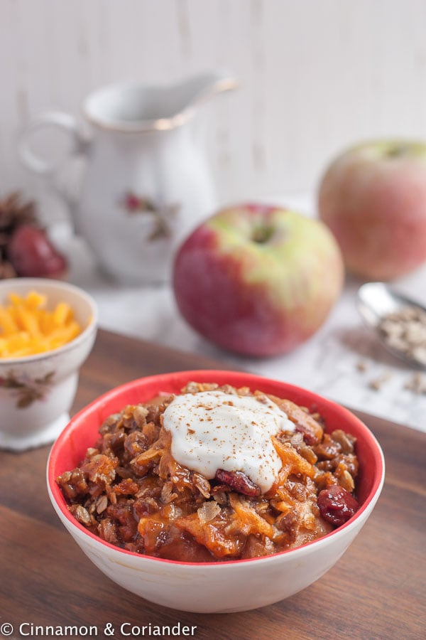a bowl of best apple crisp with cheddar oat crumble topping served with a dollop of sour cream