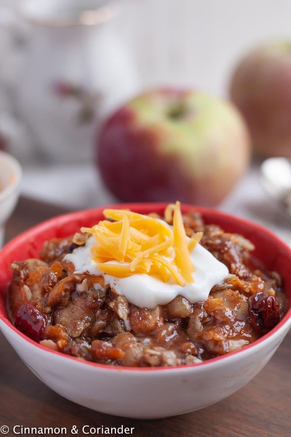 close-up of a bowl of apple crisp topped with sour cream and cheddar cheese
