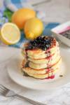 a stack of homemade fluffy pancakes with blueberry syrup spooned on top