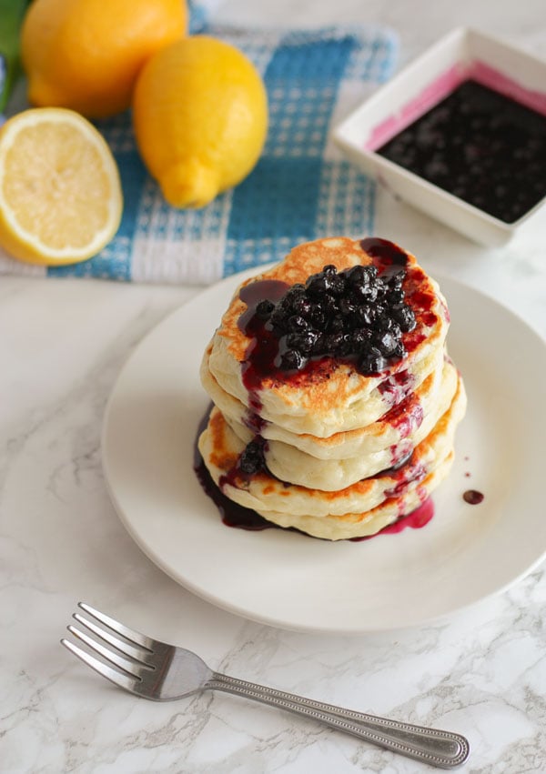 a stack of fluffy buttermilk pancakes with blueberry sauce on top
