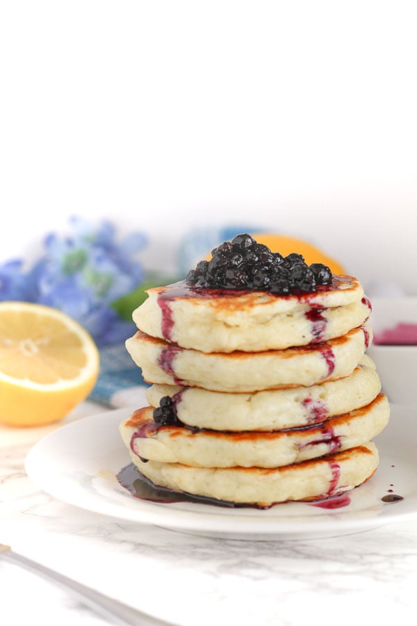 side view of a stack of fluffy buttermilk pancakes topped with blueberry sauce