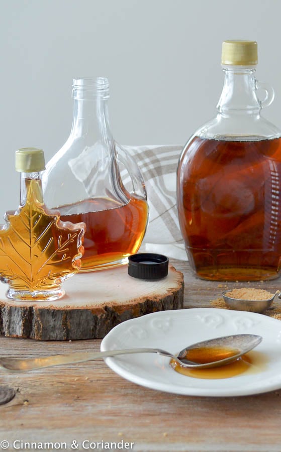 different sized and shaped bottles of maple syrup on a wooden table