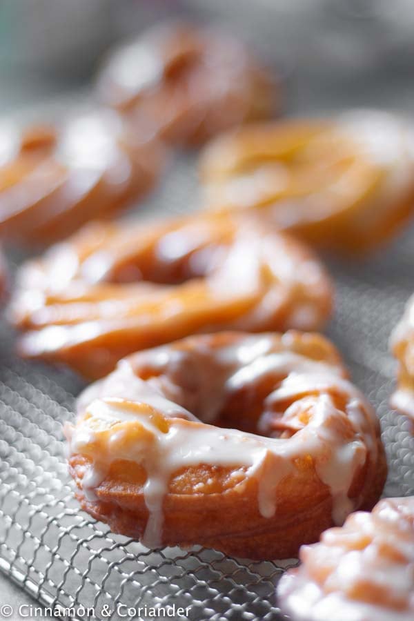 freshly glazed fried apple cider donuts cooling on a wire rack