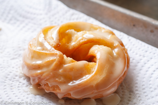 a freshly glazed French Apple Cider Cruller on a piece of kitchen paper towel