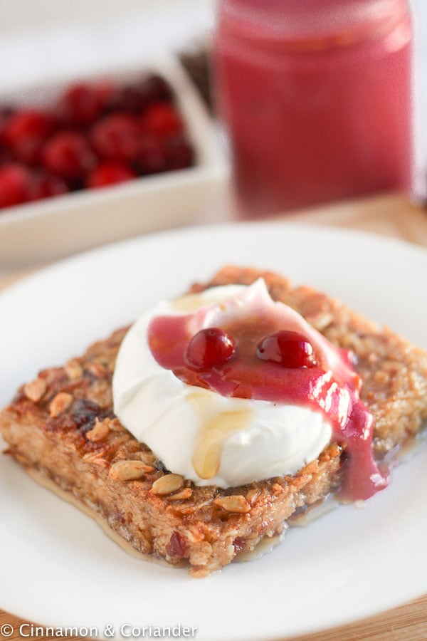 a square of pan-fried oatmeal topped with coconut yogurt and cranberry curd on a white plate