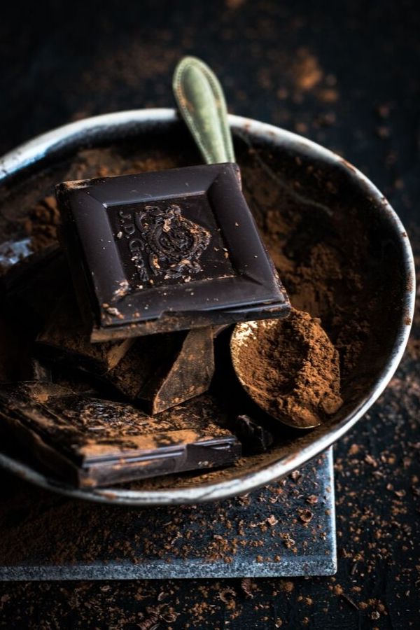 dunkle Schokolade und Kakaopulver auf einem antiken Teller 