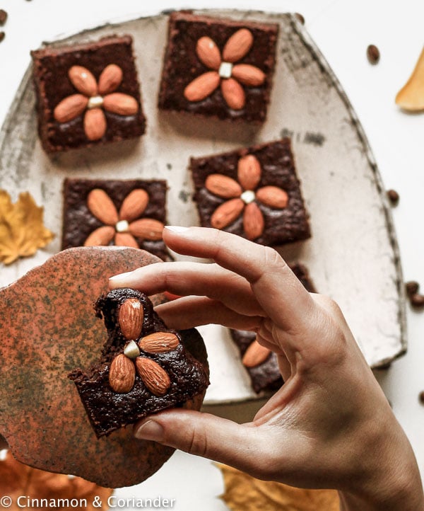 a hand holding a paleo almond flour brownie decorated with whole almonds