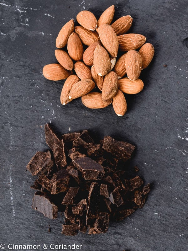 chopped dark chocolate and whole almonds on a black granite kitchen counter