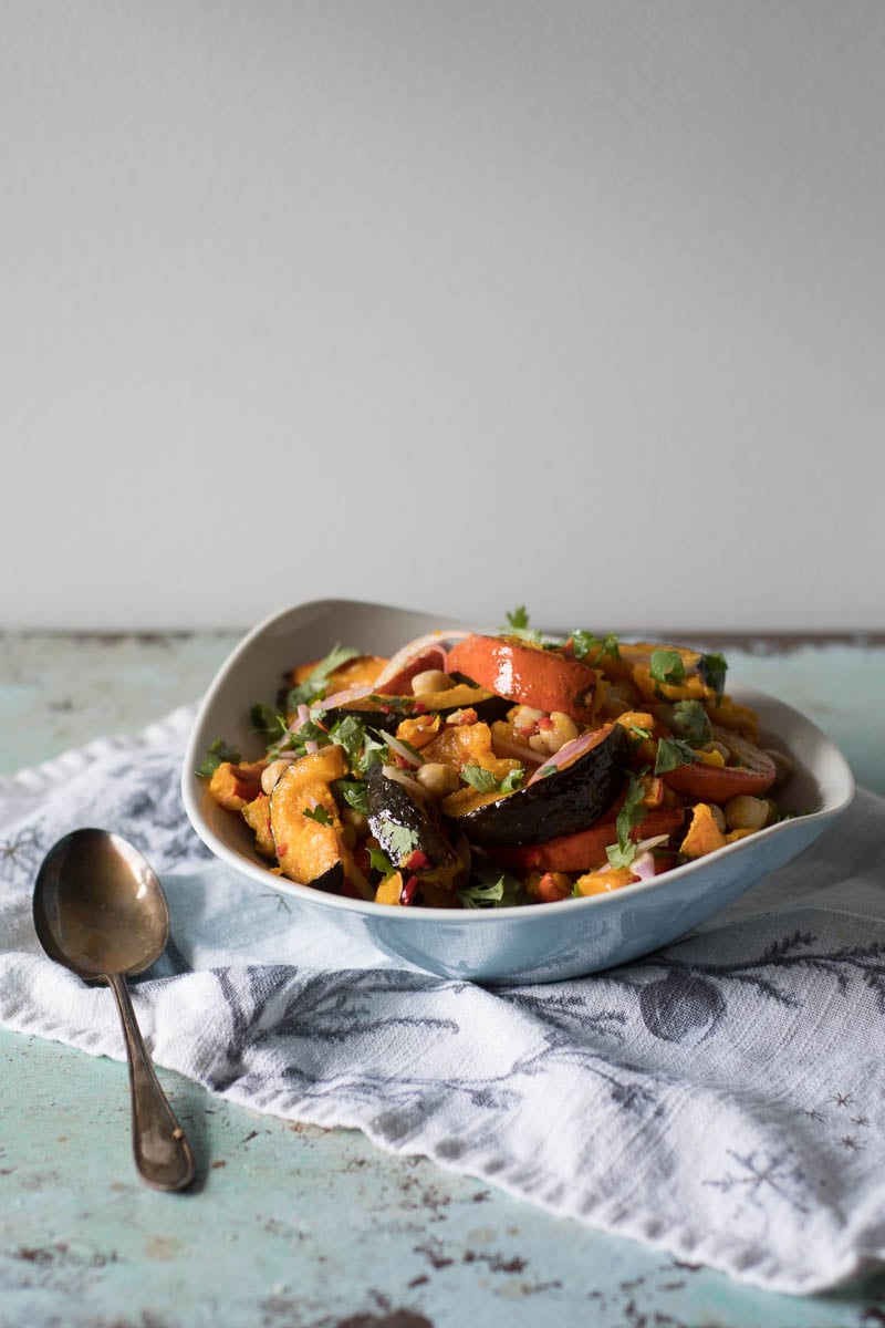 side view of a bowl of roasted squash and chickpea salad with lime dressing