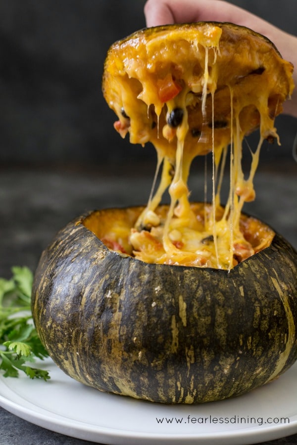 side view of a Vegetarian Stuffed Kabocha Squash with plenty of melted cheese oozing out of the squash