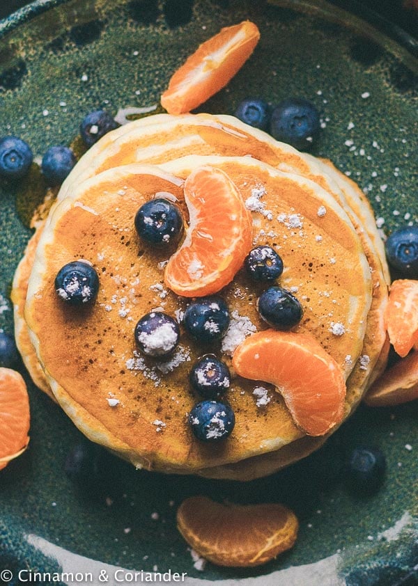 einfache vegane Pancakes mit Puderzucker, Blaubeeren und Mandarinensirup serviert