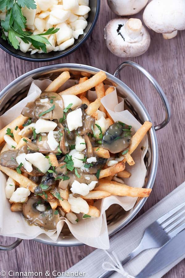 overhead shot of a serving of homemade poutine with mushrooms gravy and cheese curds