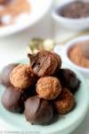 side view of homemade vegan rum balls made with black beans piled up on a blue plate