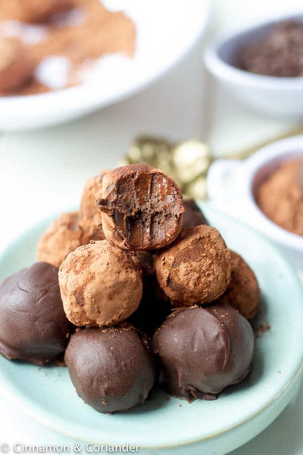 healthy easy vegan rum balls covered in dark chocolate piled up on a pale blue plate