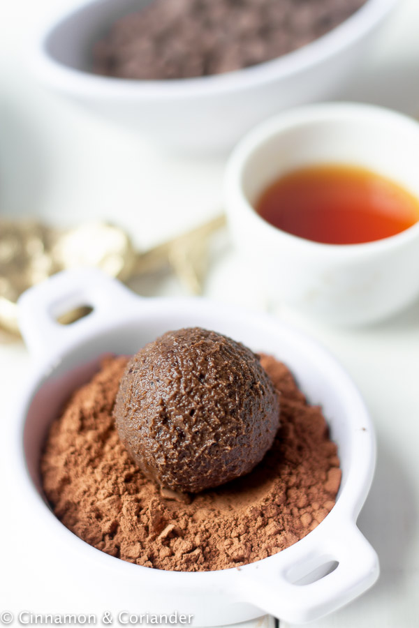 a healthy vegan rum balls being rolled in cocoa powder