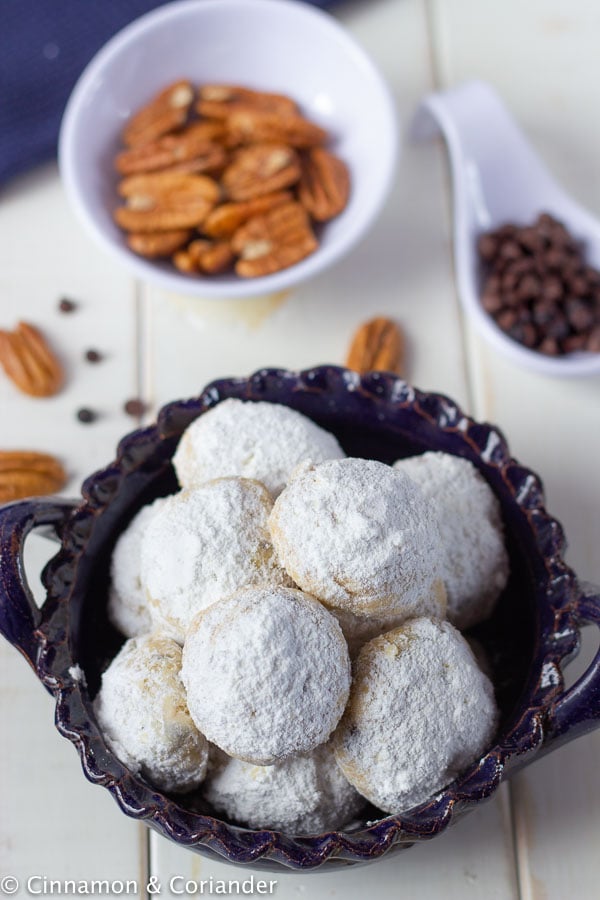 overhead shot of a small bowl with sugar-free chocolate chip snowball cookies with pecans on the side