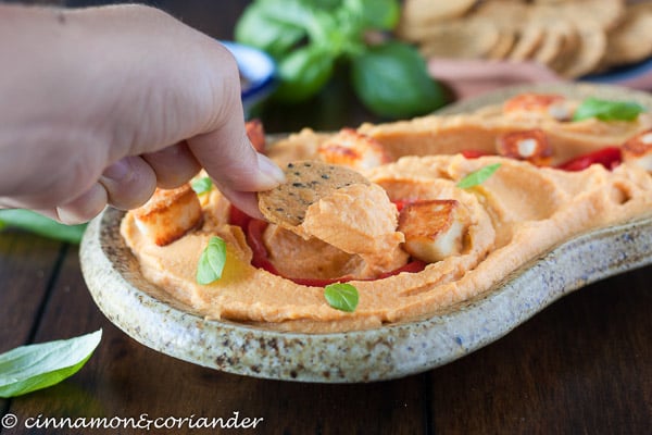 ein Pita Chip wird in eine Schale mit cremigem Hummus gedippt