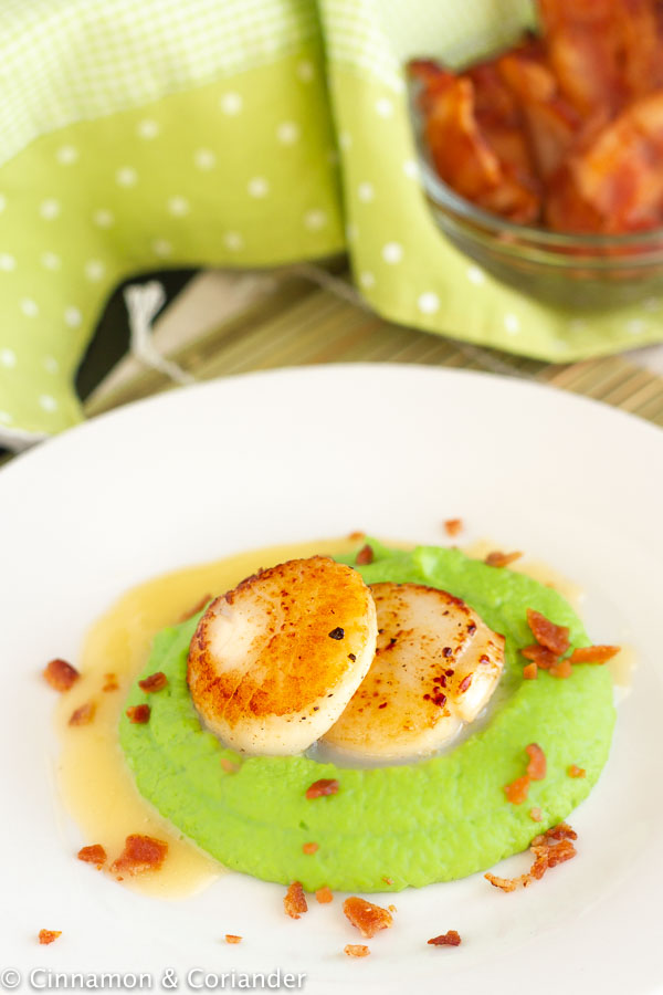 overhead shot of pan-seared scallops on pea puree with butter beurre blanc on the side