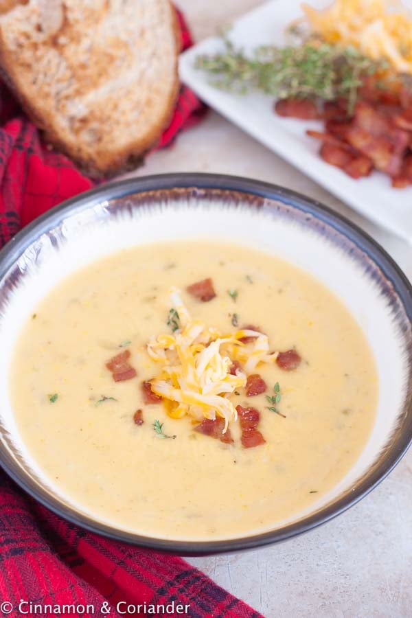 a bowl of the best Canadian beer and cheddar cheese soup topped with cheese, bacon and thyme